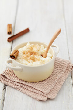 Milk rice pudding in pot with cinnamon on table