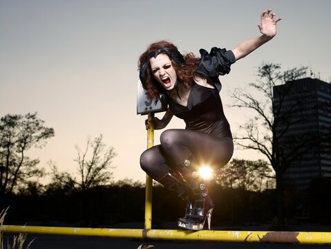 Angry woman sitting on a metal bar outdoors screaming with energy