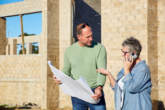 Architect and builder discussing plans on a construction site