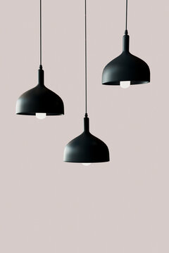 3D render of three black light fixtures hanging against pink background