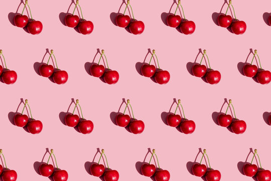 Pattern of fresh cherries on pink background