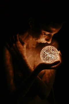 Woman contemplating a glowing light orb in the dark