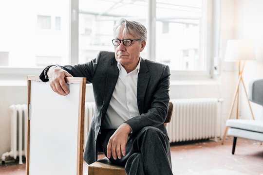 Senior businessman sitting on chair with picture frame