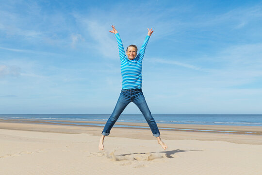 Carefree woman jumping on the sand at the North Sea