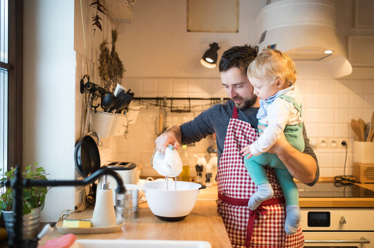 Father and baby boy in kitchen baking a cake