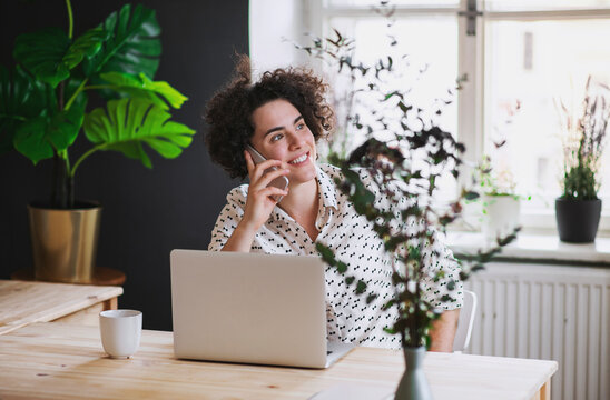 Smiling young woman on the phone in home office