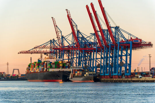 Container ship and cranes at Hamburg harbor at sunset