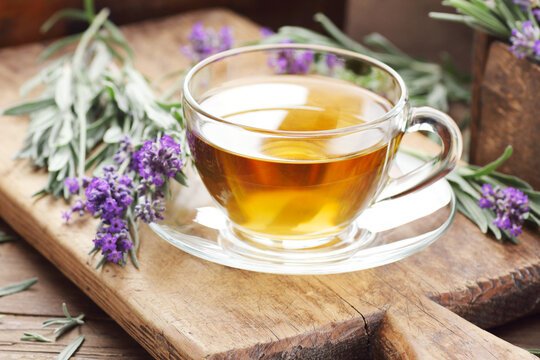 Lavender herbal tea in a glass cup with flowers on wooden rustic background, closeup, sleep and skin healing drink, natural medicine and naturopathy concept