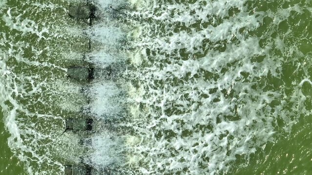 An aerial view of a paddle wheel aeration system creating strong water movement, illustrating modern aquaculture practices, oxygenation efficiency, pond management, and sustainable seafood production.