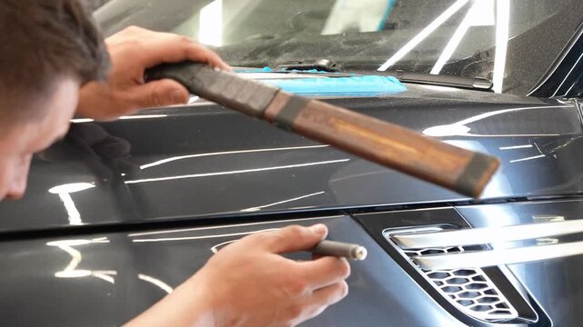 PDR. Paintless Car Dent Repair. Process of paintless dent repair on car body. The mechanic at the auto shop with tools to repair dents in car body. Body repair. A specialist repairs a dent on the car.