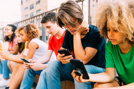 Friends using mobile phone sitting by railing