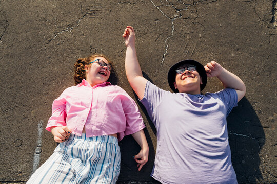 Brother and sister laughing and lying on street