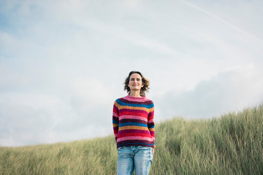 Content woman standing in the dunes, smiling