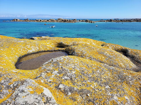 Die K&uuml;ste am Plage de Roc'h ar Gonc beeindruckt mit gelb leuchtenden Flechten auf den Granitfelsen und kleinen Gezeitent&uuml;mpeln vor dem t&uuml;rkisblauen Meer.