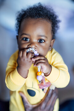 Baby girl chewing toy while held by man