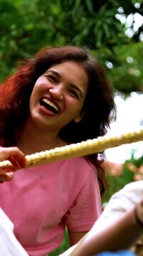 Indian family playing tug of war rassi khech in home garden, spending quality fun time together enjoying outdoor sports, cheerful Asian parents children bonding through traditional backyard activity
