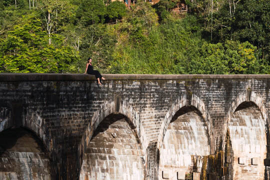 Woman sitting on iconic Nine Arches Bridge in Ella Sri Lanka