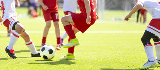 Naklejka premium Football Game For Children; Youth Soccer Action: Close-Up of Kids Legs Kicking Ball During Football Match