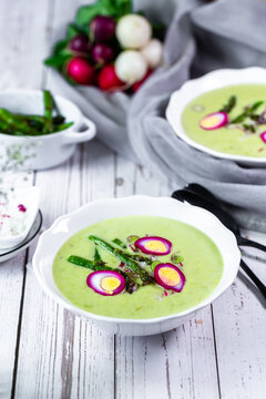 Creamy green asparagus soup with quail egg and radish