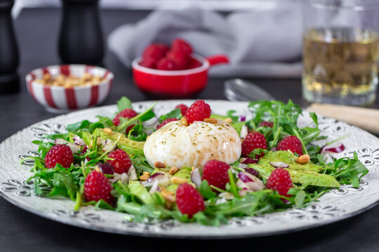 Fresh spring salad with burrata arugula avocado and raspberry
