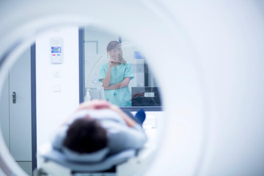 Patient in hospital during CT examination, female radiologist