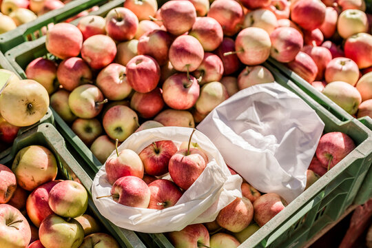 Cloth bag and plastic bag on boxes with apples on weekly market