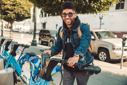 Stylish young man on the street with rental bike