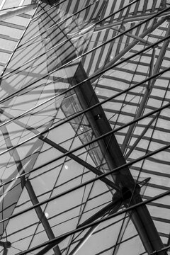Glass roof structure and monochrome lines create an abstract reflection, linking urban architecture with building interior depth and scale