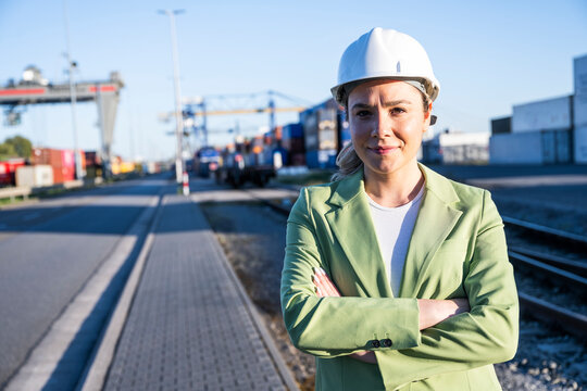 Businesswoman in hardhat standing at outdoor container terminal