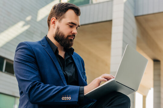 Stylish businessman working on laptop outdoors