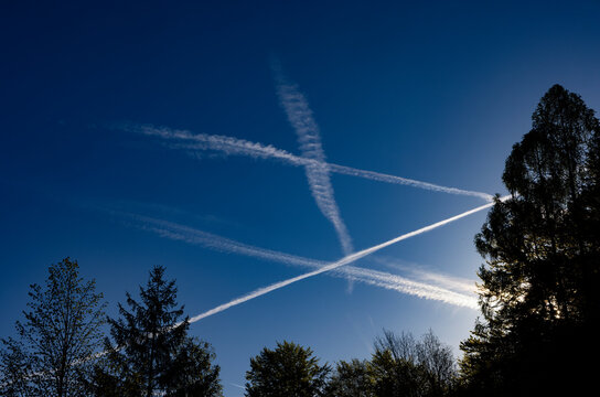 Multiple airplane contrails crisscrossing in a clear blue sky