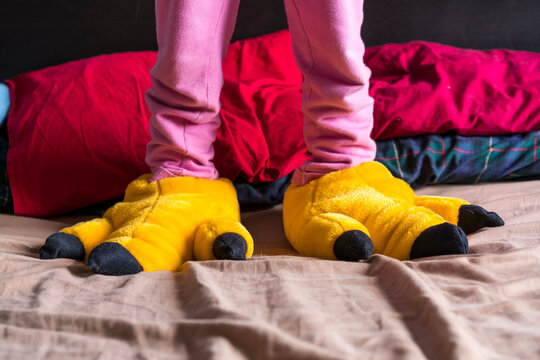 Girl standing on bed wearing yellow fun slippers