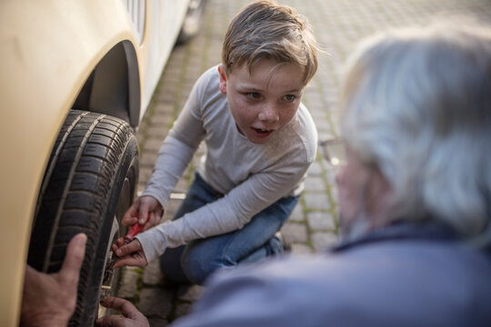 Senior man and boy changing car tire
