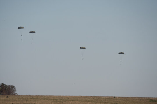 a large grey cargo plane dropping low level parachute cargo