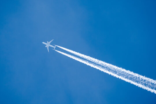 twin engined jet liner aircraft with contrails, in flight at high altitude, clear blue sky