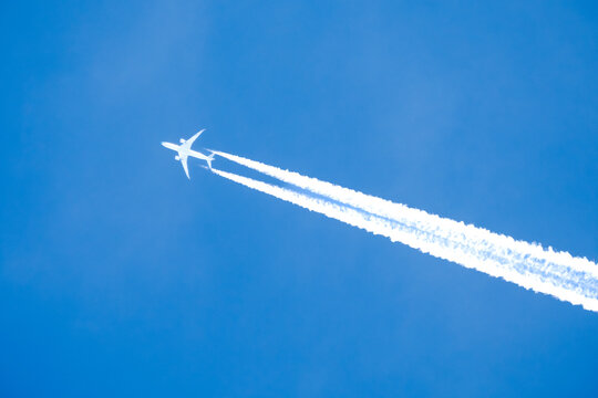 twin engined jet liner aircraft with contrails, in flight at high altitude, clear blue sky