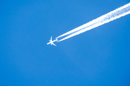twin engined jet liner aircraft with contrails, in flight at high altitude, clear blue sky