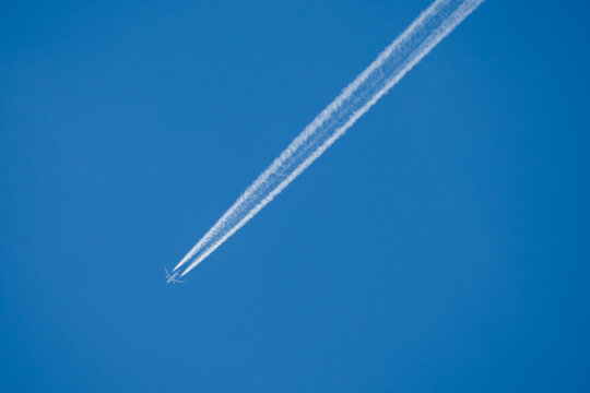 twin engined jet liner aircraft with contrails, in flight at high altitude, clear blue sky