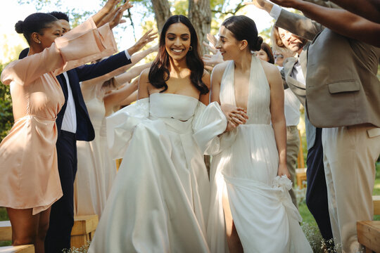 Lesbian couple exits wedding ceremony surrounded by supportive friends