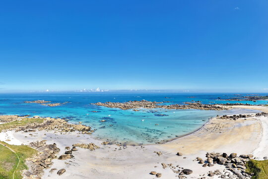 Ein atemberaubender Panorama-Ausblick auf die gesch&uuml;tzte Bucht des Plage de Roc'h ar Gonc mit glasklarem, t&uuml;rkisfarbenem Wasser, feinem Sand und markanten Riffen.