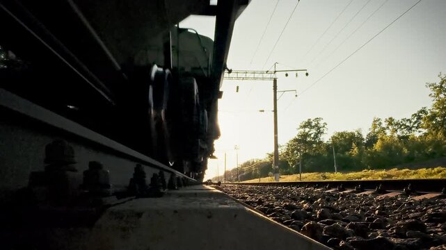 A freight train speeds through the countryside on iron rails, a close-up highlights its rotating wheelsets. The scene underscores logistics efficiency and sustainable infrastructure development
