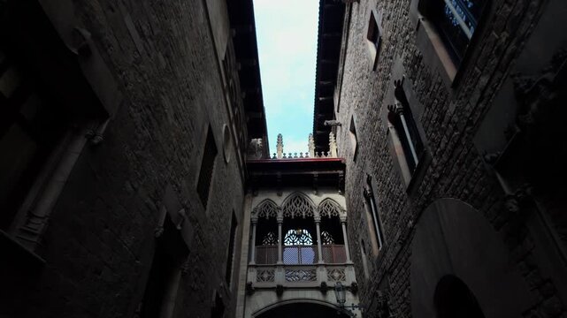Ornate neogothic architecture of the pont del bisbe, a famous landmark connecting two buildings over a narrow alley in the historic barri gotic of barcelona, spain on a bright day