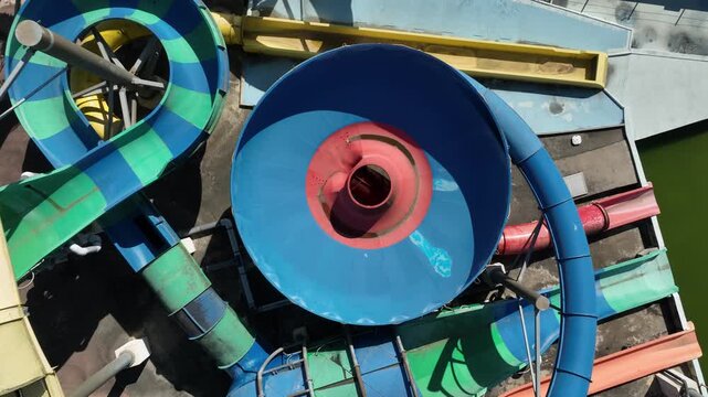 Top down aerial drone shot of colorful water slides and pools at aquapark.