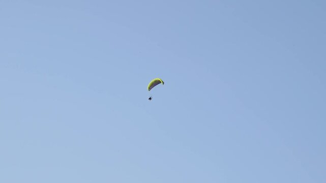 Experience paramotor flight across the blue sky in perfect weather at an open field location