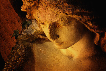 Obraz premium Close-up of a weathered angel statue illuminated by warm light.