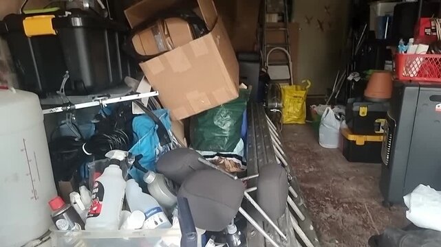 Collection of various untidy stacked household clutter and workshop tools storage in home garage