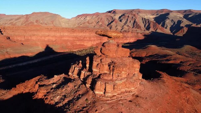 Close to wide pull back aerial drone shot of Mexican Hat Rock in southeastern Utah, near sunset with dramatic shadows.