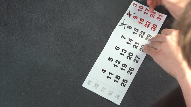 Hand Crossing out Days on a Calendar Page with a Black Felt Pen. Planning date. Copy space