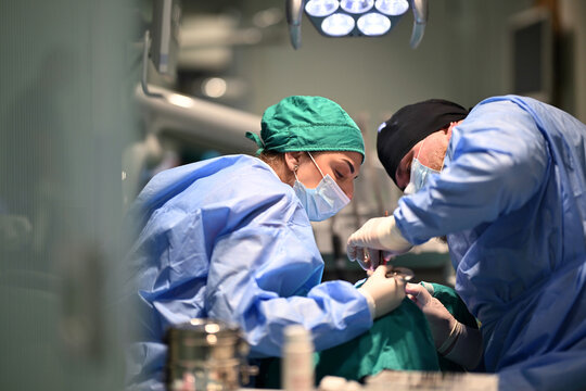 Surgeons Performing Operation In Sterile Operating Room During Surgical Team Procedure