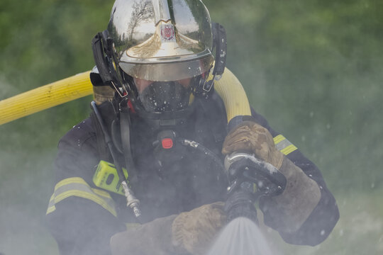 Firefighter in full protective gear operating hose during training exercise